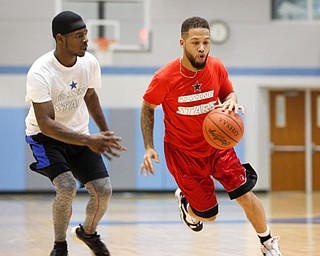 Local barber Daniel Lopez dribbles the ball past local rapper James Merchant during the Rising Stars basketball game at East High School on Sunday. EMILY MATTHEWS | THE VINDICATOR