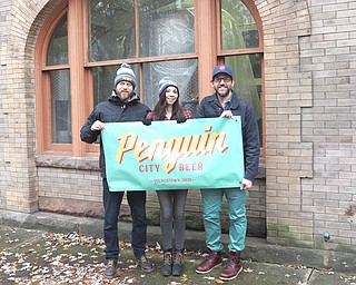 From left, Richard Bernacki, Aspasia Lyras and Michael Pontikos of Penguin City Beer display the company’s logo in front of their new brewing home at the B&O Station.