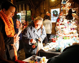 Robin Blose, of Kittanning, Pa., left, and her aunt Barb Soloski, of Youngstown, look at and buy Christmas ornaments from Lindy Young and Shawne Wilfong, both of Austintown, at Lanterman's Mill Olde Fashioned Christmas on Saturday. EMILY MATTHEWS | THE VINDICATOR