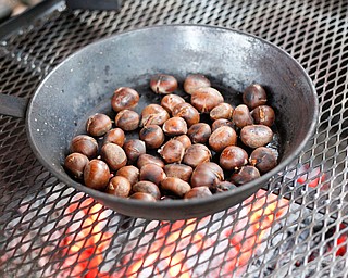 Chestnuts are roasted over a fire by Ray Novotny, of Cornersburg, at Lanterman's Mill Olde Fashioned Christmas on Saturday. EMILY MATTHEWS | THE VINDICATOR