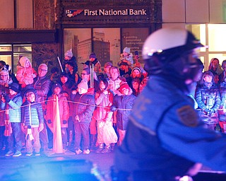 People watch as Youngstown Police officers drive by at the beginning of Youngstown's annual Holiday Parade on Friday night. EMILY MATTHEWS | THE VINDICATOR