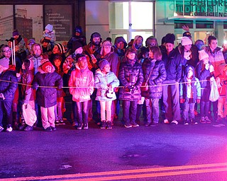 People watch as Youngstown Police officers drive by at the beginning of Youngstown's annual Holiday Parade on Friday night. EMILY MATTHEWS | THE VINDICATOR