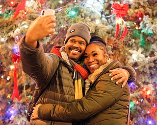 Robert Moore, of Youngstown, takes a selfie with Marquita Hall, of Youngstown, in front of the Christmas tree after the holiday parade and tree-lighting ceremony Friday night. EMILY MATTHEWS | THE VINDICATOR