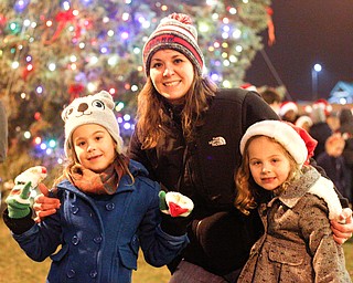 From left, Cassi Samios, 7, mom Lauren Samios, and Korie Samios, 5, all of Brookfield, pose in front of the Christmas tree after the holiday parade and tree-lighting ceremony Friday night. EMILY MATTHEWS | THE VINDICATOR