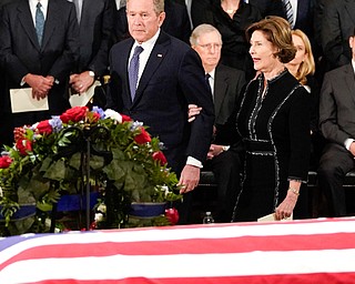 Former President George W. Bush and his wife, former first lady Laura Bush, pass by the flag-draped coffin of his father, former President George H.W. Bush, in the Capitol Rotunda in Washington on Monday afternoon.  