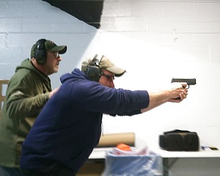 n this photo taken from a video shot on Nov. 28, 2018, Mike Carnevale places his hand on the back of Mark Hennesey while instructing him at the American Tactical Systems' indoor range in Green Island, N.Y. The application process for handgun licenses would be expanded under a bill before the New York state Legislature. The bill would require handgun applicants to turn over log-in information so investigators could look at three years' worth of Facebook, Snapchat, Twitter and Instagram postings. Google, Yahoo and Bing searches over the previous year also would be checked.