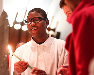 Trey Stewart, 13, an eighth grader at Akiva Academy, lights the Hanukkiah during the students' Hanukkah program at Congregation Rodef Sholom on Thursday evening. EMILY MATTHEWS | THE VINDICATOR