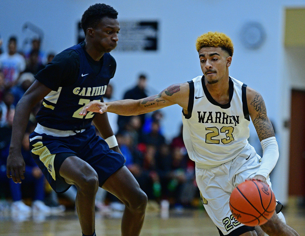 WARREN, OHIO - DECEMBER 6, 2018: Warren Harding's Dom McGhee drives on Cleveland Heights' Jesse Laster during the first half of their game Thursday night at Warren Harding High School. DAVID DERMER | THE VINDICATOR