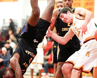 Valley Christian's Melvin Neail falls over Cardinal Mooney's Anthony Fire as he goes for the ball during the first period of their game at Cardinal Mooney on Friday night. EMILY MATTHEWS | THE VINDICATOR