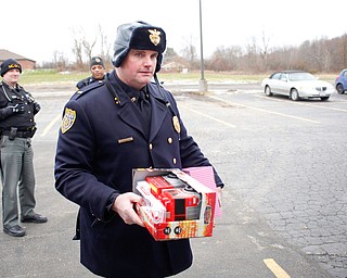 Lt. Frank Rutherford puts toys in a police van while Deputy Kirk Mines, left, and Officer Melvin Johnson watch at Youngstown Police Department's fourth annual fill a cruiser campaign in the St. Christine Church parking lot on Saturday afternoon. EMILY MATTHEWS | THE VINDICATOR