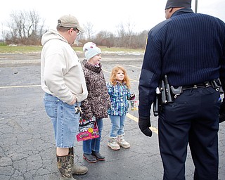 From left, Chris Philips and his daughters Kera Philips, 11, and Fiona Philips, 4, all of Austintown, hold toys to give to Officer Melvin Johnson, right, at Youngstown Police Department's fourth annual fill a cruiser campaign in the St. Christine Church parking lot on Saturday afternoon. EMILY MATTHEWS | THE VINDICATOR