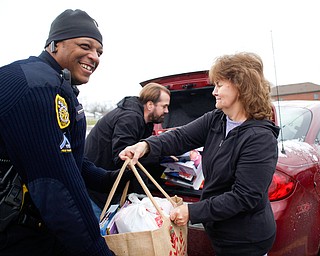 Kathy Hyland, right, of Austintown, hands a bag of toys to Officer Melvin Johnson while her son Chad Hyland, also of Austintown, gets more toys out of their trunk at Youngstown Police Department's fourth annual fill a cruiser campaign in the St. Christine Church parking lot on Saturday afternoon. EMILY MATTHEWS | THE VINDICATOR