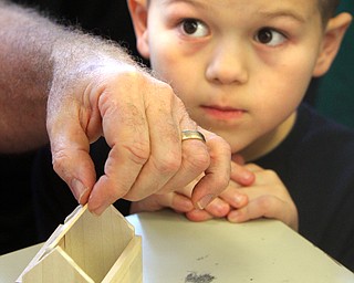 William D. Lewis The vindicator  CH Campbell school 2nd grader Ace Davis watches as Barry Tancer, former Canfield School Bd member demonstrates building wooden gingerbread house ornaments.