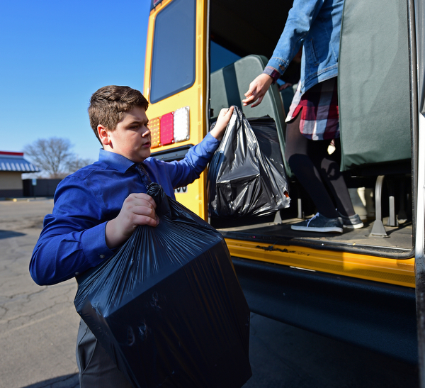 COLUMBIANA, OHIO - DECEMBER 13, 2018: Cade Hancos, an 8th grader at Crestview, is handed bags of gifts from the back of a school bus, Thursday morning in Columbiana. DAVID DERMER | THE VINDICATOR