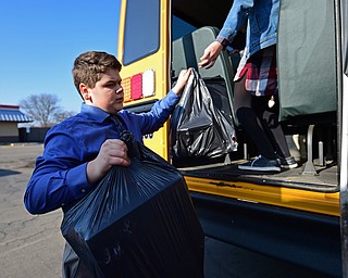 COLUMBIANA, OHIO - DECEMBER 13, 2018: Cade Hancos, an 8th grader at Crestview, is handed bags of gifts from the back of a school bus, Thursday morning in Columbiana. DAVID DERMER | THE VINDICATOR