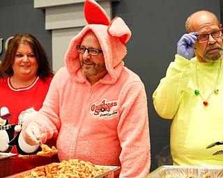 Joe Mazzocca Jr., a 3rd Ward Councilman, center, dressed in a pink bunny suit from A Christmas Story, serves lunch with his wife Teresa Mazzocca, left, and Tom Mesaros, right, during Campbell's annual Lunch with Santa at St. Lucy Palermo Hall on Sunday afternoon. EMILY MATTHEWS | THE VINDICATOR