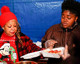 Yvette Kirksey, left, a teacher at Youngstown City Schools, and Seannille McAre, of Youngstown, serve pasta and meatballs at Flambeau's Live's pasta dinner fundraiser to raise money for the funeral of the five fire victims on Tuesday evening. EMILY MATTHEWS | THE VINDICATOR