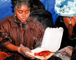 Seannille McAre, left, and Sarina Chatman, both of Youngstown, serve pasta and meatballs at Flambeau's Live's pasta dinner fundraiser to raise money for the funeral of the five fire victims on Tuesday evening. EMILY MATTHEWS | THE VINDICATOR