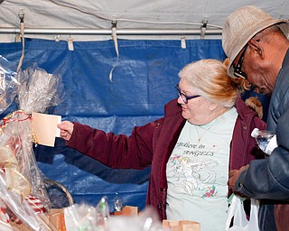 Lois Martin-Uscianowski, left, who runs South Side Community Garden, and Ernest Riggins, of Youngstown, look at raffle baskets at Flambeau's Live's fundraiser for the funeral of the five fire victims on Tuesday evening. EMILY MATTHEWS | THE VINDICATOR