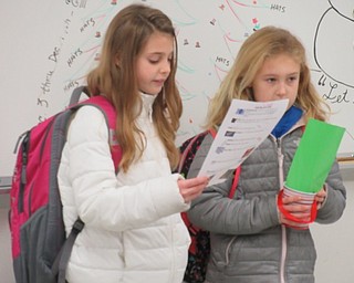 Neighbors | Jessica Harker.Delaney Demetrios and Halle Argiro read a list of supplies kept in a bucket filler bucket on Dec. 3 to students and teachers at Poland McKinley School.