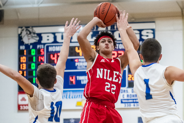 DIANNA OATRIDGE | THE VINDICATOR Niles' Corbin Foy (22) puts up a 3-point shot between Lakeview defenders AJ McClellan (10) and Daniel Evans (1) during the Bulldogs' 68-41 victory in Cortland on Friday.