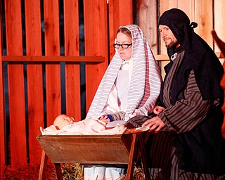 Mary, portrayed by Rachael Lanham, Joseph, portrayed by Brice Harris, kneel beside their baby Jesus while Fancy Pants the donkey, from Felger Exotics, watches them during the Live Nativity at Zion Lutheran Church in Cornersburg on Sunday evening. EMILY MATTHEWS | THE VINDICATOR