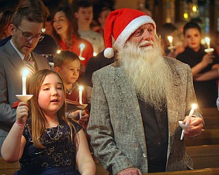 William D. Lewis The Vindicator Lou Stark and his grandaughter Miley Harshbarger, 7, hold candles during a Christmas Eve service at Trinity United Methodist church in Youngstown. They are from Youngstown. Stark says he has had the beard for several years and people often tell him he resembles a certain bearded gentleman who is very popular on Christmas Eve.