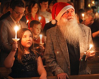 William D. Lewis The Vindicator Lou Stark and his grandaughter Miley Harshbarger, 7, hold candles during a Christmas Eve service at Trinity United Methodist church in Youngstown. They are from Youngstown. Stark says he has had the beard for several years and people often tell him he resembles a certain bearded gentleman who is very popular on Christmas Eve.