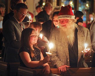 William D. Lewis The Vindicator Lou Stark and his grandaughter Miley Harshbarger, 7, hold candles during a Christmas Eve service at Trinity United Methodist church in Youngstown. They are from Youngstown. Stark says he has had the beard for several years and people often tell him he resembles a certain bearded gentleman who is very popular on Christmas Eve.