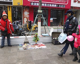 In this Saturday, Dec. 22, 2018, photo, a man sells Christmas decorations on a street of Zhangjiakou in northern China's Hebei province. At least four Chinese cities and one county have restricted Christmas celebrations this year. Churches in another city have been warned to keep minors away from Christmas, and at least ten schools nationwide have curtailed Christmas on campus, The Associated Press has found.