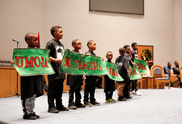 Members of the Harambee Youth Organization hold up the Seven Principles of Blackness during a Kwanzaa celebration at New Bethel Baptist Church on Wednesday night. EMILY MATTHEWS | THE VINDICATOR