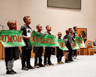 Members of the Harambee Youth Organization hold up the Seven Principles of Blackness during a Kwanzaa celebration at New Bethel Baptist Church on Wednesday night. EMILY MATTHEWS | THE VINDICATOR