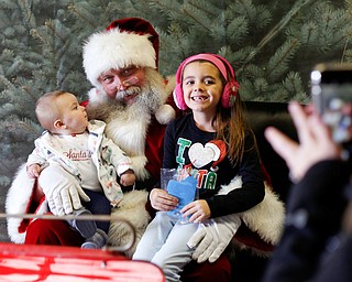 Pasley Gaetano, 8 months, left, and Gabby Baetano, 6, both of Canfield, sit with Santa while their mom, Theresa Valek, takes a photo at Santa's Winter Barn at Mill Creek MetroParks barn in Canfield on Sunday. EMILY MATTHEWS | THE VINDICATOR
