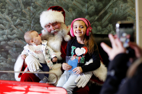 Pasley Gaetano, 8 months, left, and Gabby Baetano, 6, both of Canfield, sit with Santa while their mom, Theresa Valek, takes a photo at Santa's Winter Barn at Mill Creek MetroParks barn in Canfield on Sunday. EMILY MATTHEWS | THE VINDICATOR
