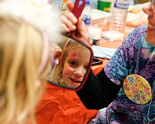 Alexa Shook, 5, of Canfield, looks at herself in a mirror after getting her face painted by Sara Siegfried, with The Laughing Ladybug, inside 20 Federal Place during First Night Youngstown Monday night. EMILY MATTHEWS | THE VINDICATOR