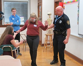 Neighbors | Jessica Harker.Poland Officer Steve Kent walked student Ella Gaffney across the floor in drunk goggles Dec. 14 during his presentation to eighth-grade students during Career Day.