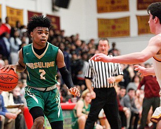 Ursuline's Daysean Harris dribbles the ball while Cardinal Mooney's Matt Brennan tries to block him during their game at Cardinal Mooney on Friday night. EMILY MATTHEWS | THE VINDICATOR