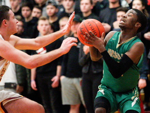 Ursuline's RJ Clark looks to pass the ball as Cardinal Mooney's John Murphy tries to block him during their game at Cardinal Mooney on Friday night. EMILY MATTHEWS | THE VINDICATOR