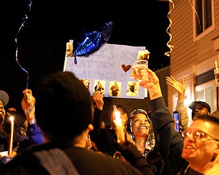 People hold up a poster and candles for Matthew Burroughs as balloons are released at the end of a vigil for Burroughs outside of his Royal Mall Apartment on Saturday night. EMILY MATTHEWS | THE VINDICATOR