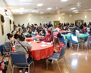 People eat before presents are distributed during Three Kings Day at OCCHA on Saturday afternoon. EMILY MATTHEWS | THE VINDICATOR