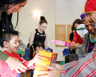 Malachi Muniz, 5, receives a present with his mother Sheila Santiago, of Youngstown, from one of the Three Kings, George Lopez, of Youngstown, during Three Kings Day at OCCHA on Saturday afternoon. EMILY MATTHEWS | THE VINDICATOR