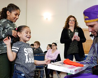 Abrianalis Saldana, 11, right, and Joselyn Bonilla, 6, both of Youngstown, receive presents from one of the Three Kings, Carlos Rosario, of Youngstown, during Three Kings Day at OCCHA on Saturday afternoon. EMILY MATTHEWS | THE VINDICATOR