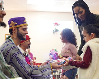 Sheylynn Muniz, 9, right, with her mom Sheila Santiago, and Daysha Ocasio, 9, all of Youngstown, receive gifts from the Three Kings, from left, Jose Rene Vazquez, Carlos Rosario, and George Lopez, all of Youngstown, during Three Kings Day at OCCHA on Saturday afternoon. EMILY MATTHEWS | THE VINDICATOR