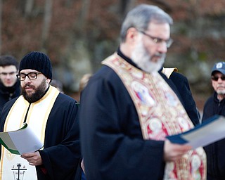 Father Michael Gavirols, left, speaks while Father Tom Constantine listens with others during the Blessing of the Waters Service at Lake Glacier in Mill Creek Park on Sunday afternoon. EMILY MATTHEWS | THE VINDICATOR