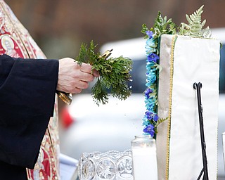 Father Tom Constantine dips basil into holy water during the Blessing of the Waters Service at Lake Glacier in Mill Creek Park on Sunday afternoon. EMILY MATTHEWS | THE VINDICATOR