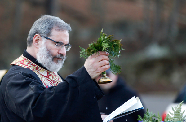 Father Tom Constantine lifts basil after dipping it in holy water during the Blessing of the Waters Service at Lake Glacier in Mill Creek Park on Sunday afternoon. EMILY MATTHEWS | THE VINDICATOR