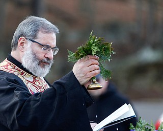 Father Tom Constantine lifts basil after dipping it in holy water during the Blessing of the Waters Service at Lake Glacier in Mill Creek Park on Sunday afternoon. EMILY MATTHEWS | THE VINDICATOR