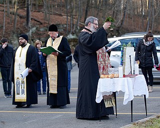 Father Tom Constantine lifts basil after dipping it in holy water during the Blessing of the Waters Service at Lake Glacier in Mill Creek Park on Sunday afternoon. EMILY MATTHEWS | THE VINDICATOR