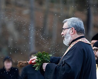 Father Tom Constantine blesses attendees with holy water during the Blessing of the Waters Service at Lake Glacier in Mill Creek Park on Sunday afternoon. EMILY MATTHEWS | THE VINDICATOR