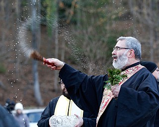 Father Tom Constantine blesses attendees with holy water during the Blessing of the Waters Service at Lake Glacier in Mill Creek Park on Sunday afternoon. EMILY MATTHEWS | THE VINDICATOR